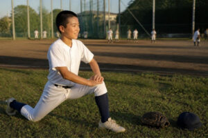 練習前にストレッチをする野球少年のイメージ